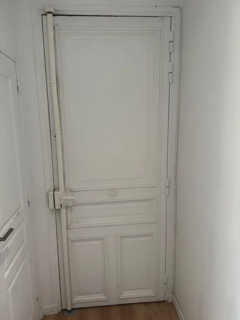 Barre de pivot Securystar installée sur toute la hauteur d'une porte blanche, avenue de Saxe, Paris