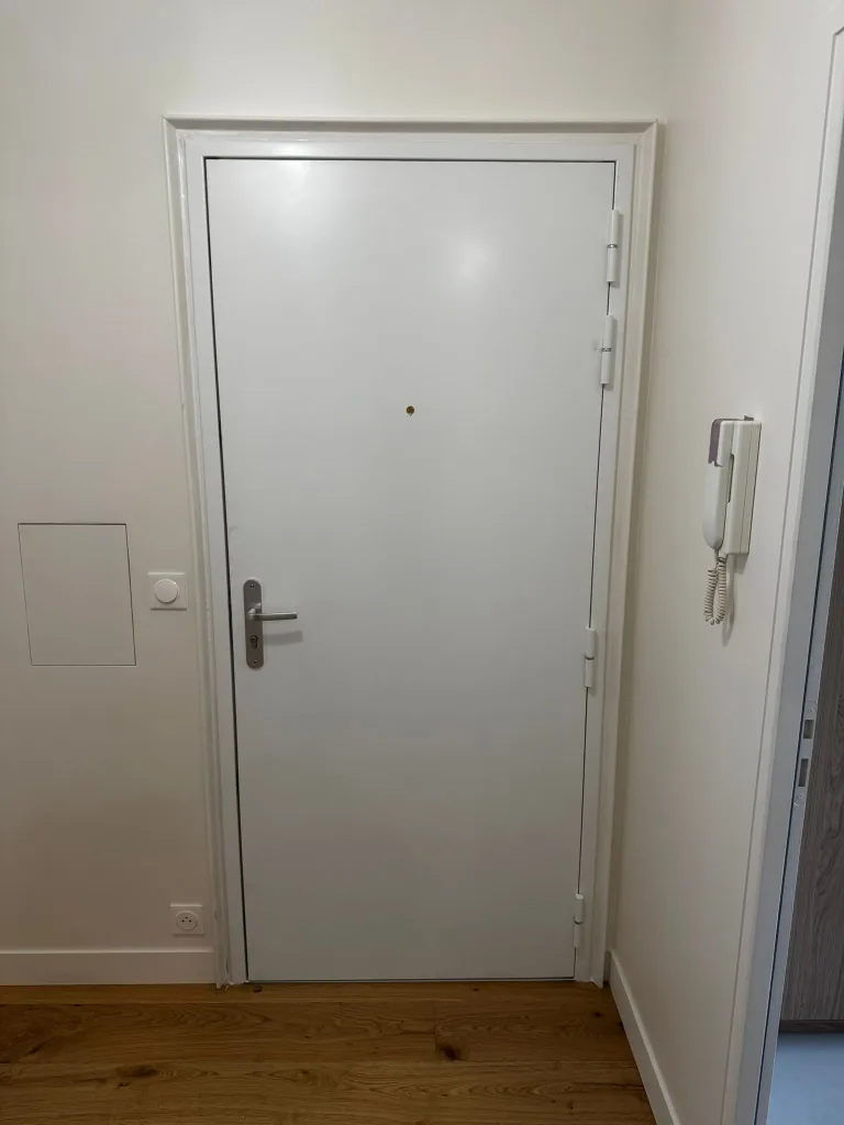 Porte blindée blanche équipée d'une serrure 3 points encastrée, rue Maurice Maignen, Paris 15e