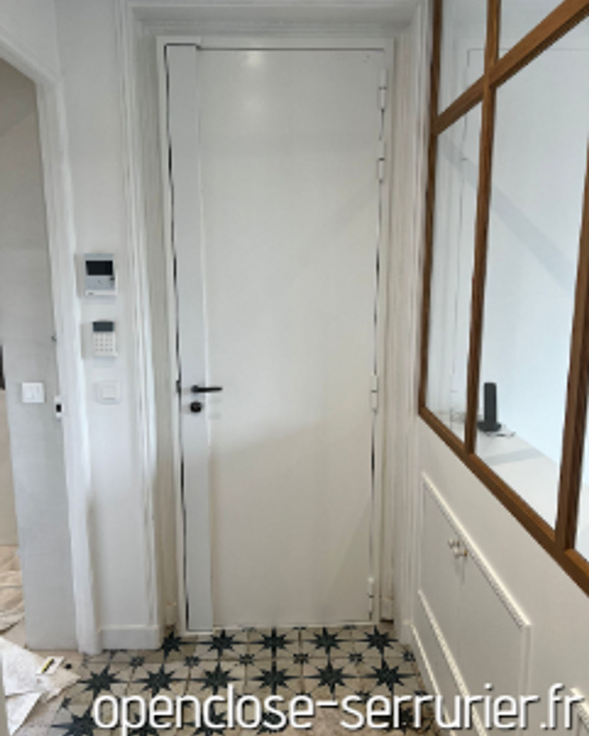 Porte palière blanche blindée avec interphone, entrée d'appartement carrelée à Paris 15e